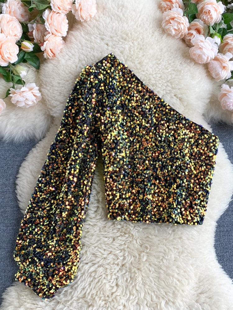 Saffron glitter one-shoulder top: voeg glamour toe aan je avondlook met sprankelende pailletten en een trendy asymmetrisch ontwerp. Perfect voor feestjes en speciale gelegenheden. Verkrijgbaar in goud, wit en blauw/goud. Combineer met rokken, broeken of jeans voor veelzijdige styling. Comfortabele pasvorm en opvallend design voor een zelfverzekerde uitstraling. Bestel nu en laat je stijl stralen!